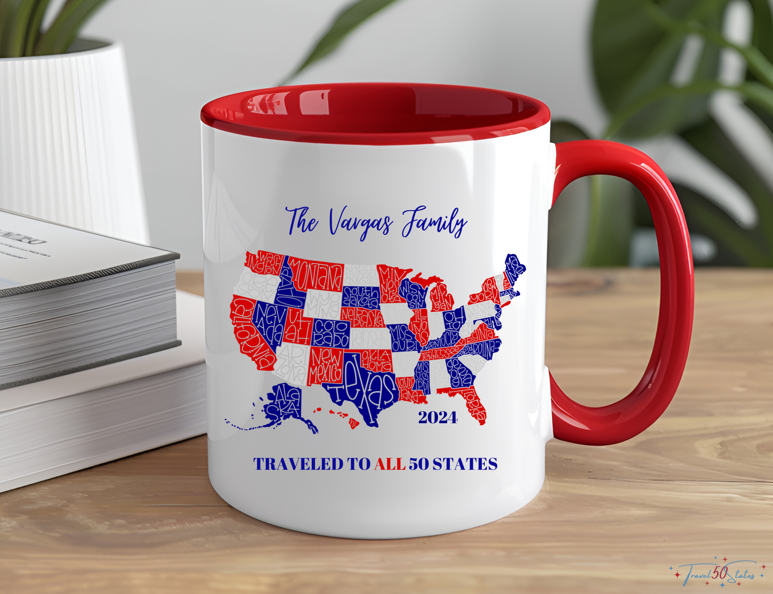 red white blue United States map with personalized name and traveled to all 50 states printed on ceramic coffee mug, 11oz. Sitting on table next to stack of books. green plant in background.